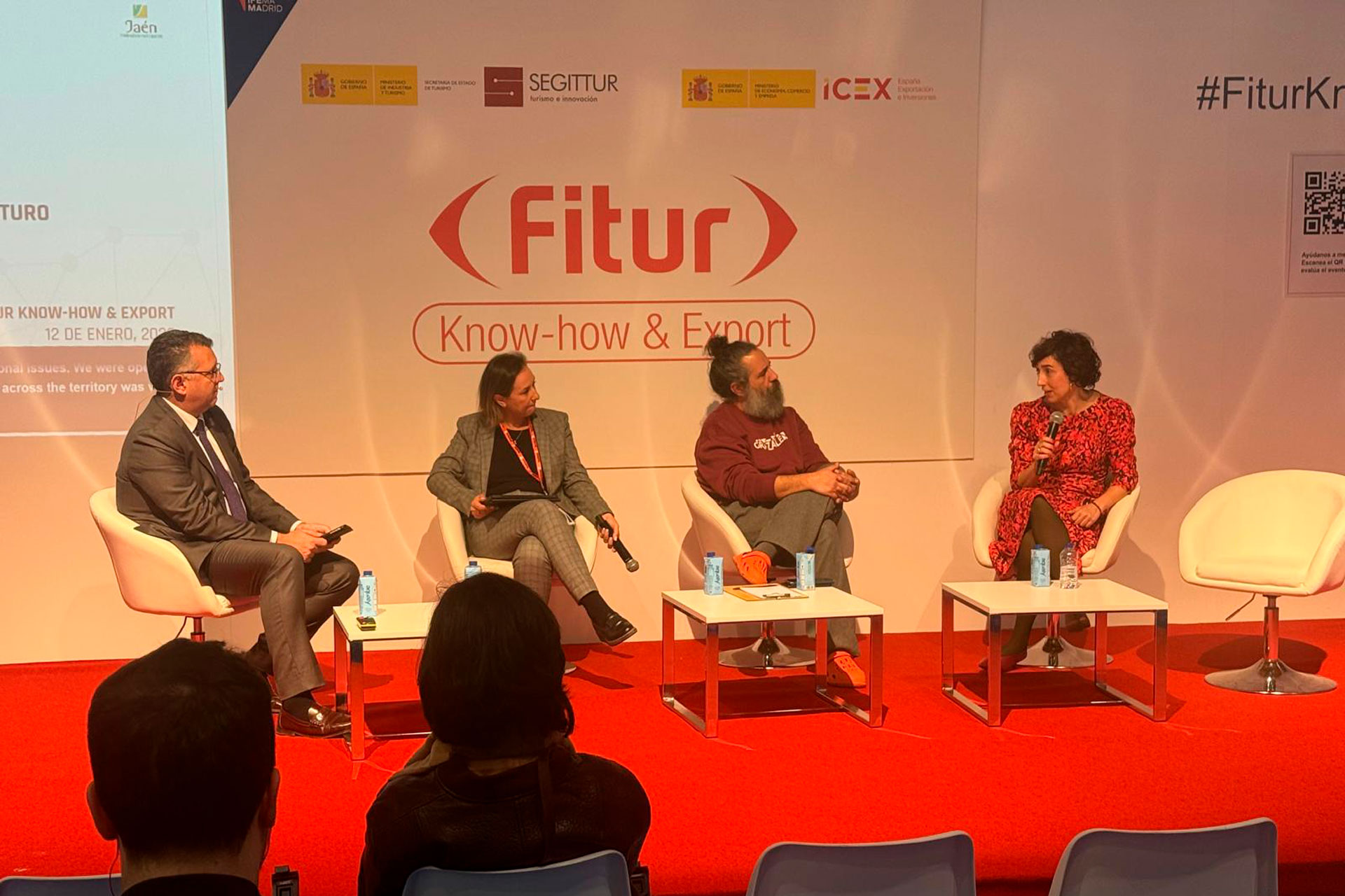 Panel de expertos sobre exportación en la Feria Fitur 2026: cuatro participantes en el escenario con logos de SEGITUR e ICEX, hablando sobre Know-how & Export