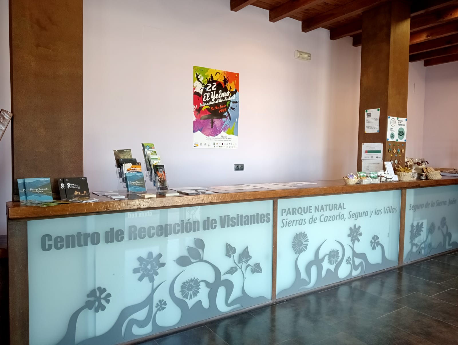 Mostrador del Centro de Recepción de Visitantes del Parque Natural Sierras de Cazorla, Segura y las Villas, con folletos informativos y cartel promocional.